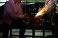 The worker uses cutting machine to cut metal, focus on flash light line of sharp spark,in low Light