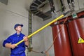 Worker uses insulating stick to earth grounding transformer.