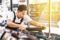 Worker uses orbital polisher by his hands, polishing on the black car hood in an auto repair shop. Auto car repair service center