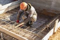 A worker uses steel tying wire to fasten steel rods to reinforcement bars. Reinforced concrete structures - knitting of a metal