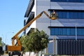 Worker using an  articulated boom lift beside a building exterior Royalty Free Stock Photo