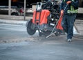 Construction worker using an asphalt saw cutting machine to excavate street