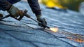 A worker using a blowtorch to melt and secure seams between different sections of roofing material Royalty Free Stock Photo
