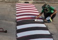 Worker using brush for painting white line on the road