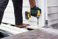 A worker is using a cordless power drill to fasten exterior floor boards. Royalty Free Stock Photo