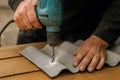 Worker using electric drill to make precise hole in gray fiber cement roofing sheet on wooden workbench for construction project Royalty Free Stock Photo