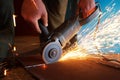 A worker using grinder cut metal.