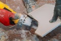 Worker using grinder tool to cut tile with dust in background Royalty Free Stock Photo