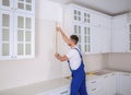 Worker using measuring tape while installing new furniture in kitchen Royalty Free Stock Photo