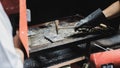 Worker using metal hammer to hit the steel after welding. Other equipments like helmet and brush were placed on the workbench.
