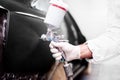 Worker using a paint spray gun for painting a car