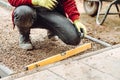 Worker using pavement slabs and level to build stone sidewalk. Close up of construction worker installing and laying pavement ston