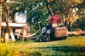 Worker using professional lawn mower for trimming backyard grass. Lansdscaping works in progress