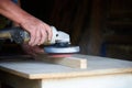 A worker using a sanding machine works with wood in a carpenter`s workshop