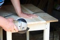 A worker using a sanding machine works with wood in a carpenter`s workshop