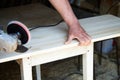 A worker using a sanding machine works with wood in a carpenter`s workshop