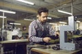 Worker using special tools and making new leather boots at workshop of shoe factory Royalty Free Stock Photo