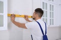 Worker using spirit level while installing furniture in kitchen Royalty Free Stock Photo