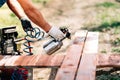 Worker using spray gun for painting brown timber