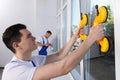 Worker using suction lifters during plastic window installation indoors Royalty Free Stock Photo