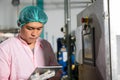 Worker using tablet in beverage factory oversees soda water filling