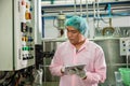 Worker using tablet in beverage factory oversees soda water filling