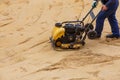 Worker using vibratory plate compactor for compaction sand during path construction. Royalty Free Stock Photo