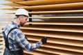 A worker varnishes boards for the construction of a wooden house. Royalty Free Stock Photo