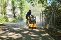 Worker with vibratory plate compacts sand before laying paving slabs in Perm, Russia