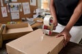 Worker of warehouse sealing packed cardboard box with order with cellotape Royalty Free Stock Photo