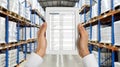 A worker in a warehouse stands in an aisle and looks at a tablet that displays a data chart Royalty Free Stock Photo