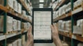 A worker in a warehouse stands in an aisle and looks at a tablet that displays a data chart Royalty Free Stock Photo