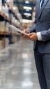 A worker in a warehouse stands in an aisle and looks at a tablet that displays a data chart Royalty Free Stock Photo