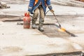 A worker warms up old asphalt with a gas burner on a repaired section of the road Royalty Free Stock Photo