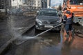 A worker washes the street in places where cars are parked