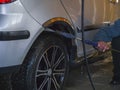 Worker washes the wheel of a car