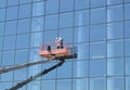 Worker washes the Windows on the glass facade of a skyscraper, standing on the platform of a crane