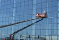 Worker washes the Windows on the glass facade of a skyscraper, standing on the platform of a crane