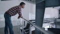 Worker watching milking facility leaning on railings. Agro engineer inspecting.