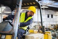 worker wearing helmet with driving forklift backwards in warehouse Royalty Free Stock Photo