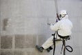 Worker wearing a protective gear cleaning a stone faceade in rope access