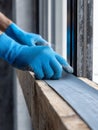 Worker wearing protective gloves installing or applying a sealing strip around window edges during construction or renovation work Royalty Free Stock Photo