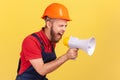 Worker wearing protective helmet holding megaphone and screaming with aggressive expression. Royalty Free Stock Photo