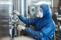 Worker wearing protective suit and mask operating equipment at chemical factory Royalty Free Stock Photo