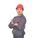 Worker wearing a red hard hat holding a wrench in hand standing in front of white background with his arms Royalty Free Stock Photo