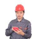 Worker wearing red hard hat is using calculator to calculate Royalty Free Stock Photo