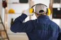 Worker wearing safety headphones indoors, back view. Hearing protection device