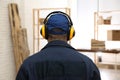 Worker wearing safety headphones indoors, back view. Hearing protection device Royalty Free Stock Photo