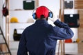 Worker wearing safety headphones indoors, back view. Hearing protection device