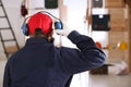 Worker wearing safety headphones indoors, back view. Hearing protection device Royalty Free Stock Photo